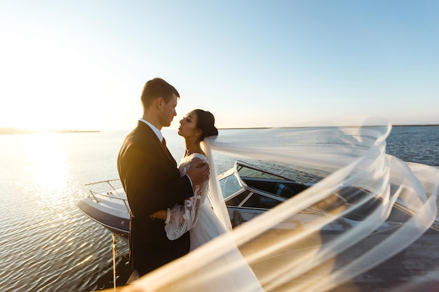 Mooie bruid en stijlvolle bruidegom samen op de brug tegen de achtergrond van de boot Together Wedding