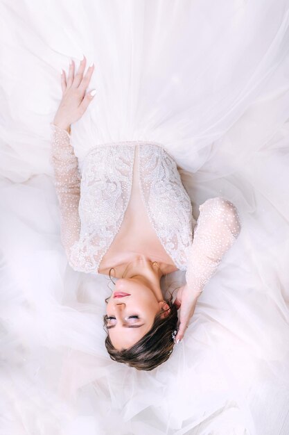 Mooie bruid in een trouwjurk liggend op de jurk Uitzicht vanaf