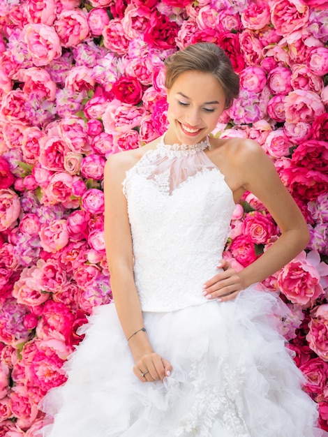 Mooie bruid in een trouwjurk poseren op een decoratieve roze bloemen.