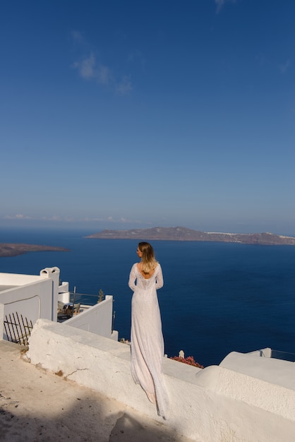 Mooie bruid in een witte jurk poseren tegen de achtergrond van de Middellandse Zee in Thira, Santorini.