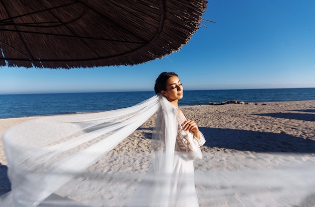 Mooie bruid in witte jurk in de zon wandelingen langs het zandstrand Elegante bruid in de zon