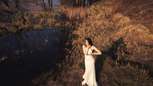 Mooie bruid in witte jurk poseren in de buurt van meer. Bruiloft inspiratie.