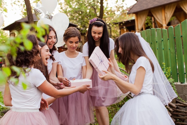 Mooie bruid opent cadeau van vriendinnen op vrijgezellenfeest modevakanties en feestconcept