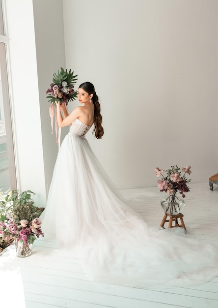 Mooie bruid poseren in trouwjurk in een witte foto Studio Wedding Bouquet of flowers