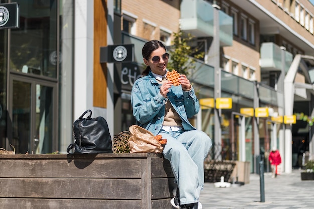 Mooie brunette 20-30s genietend van heerlijk eten van afhaalrestaurant op straat tijdens de lunch