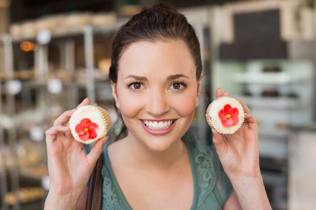 Mooie brunette die een cupcake toont