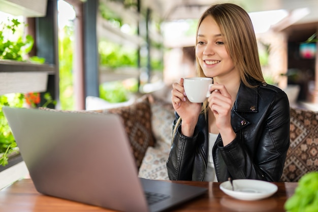 Mooie brunette die een notitieboekje gebruikt terwijl ze koffie drinkt in café