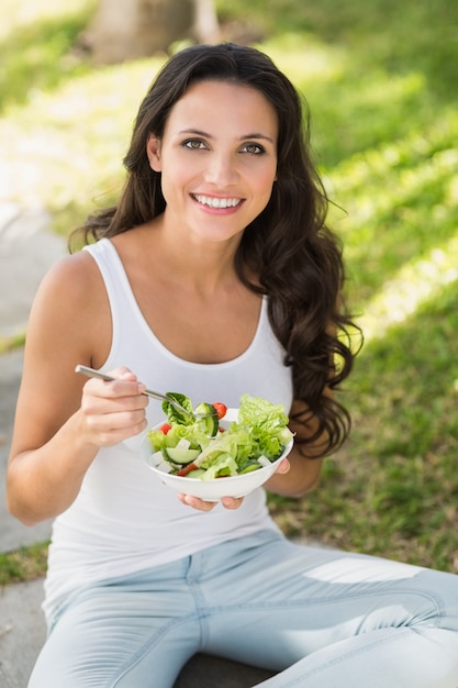 Mooie brunette die kom salade eet