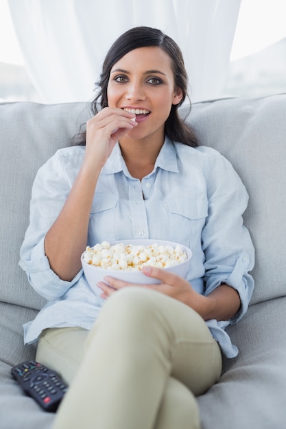 Mooie brunette die op TV met pop graan let