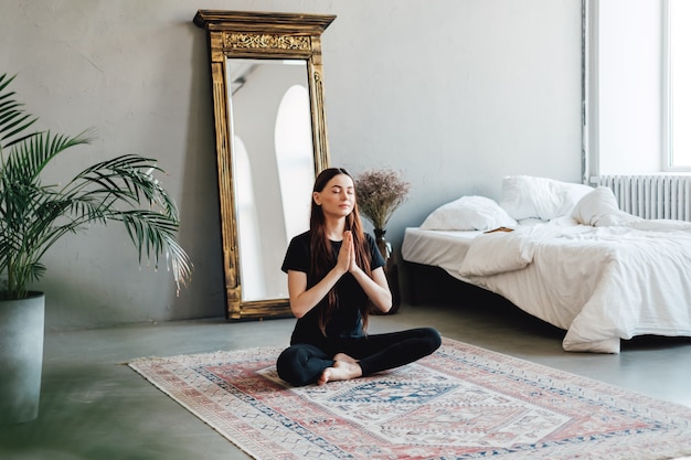 Mooie brunette fitness vrouw mediteren, yoga binnenshuis thuis doen
