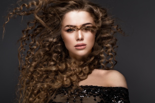 Mooie brunette in beweging met een perfect krullend haar en klassieke make-up Beauty face