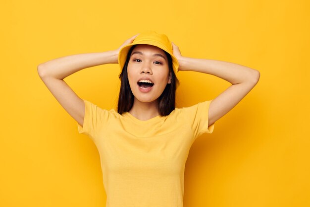 Mooie brunette in een gele t-shirt en hoed poseren emoties gele achtergrond ongewijzigd