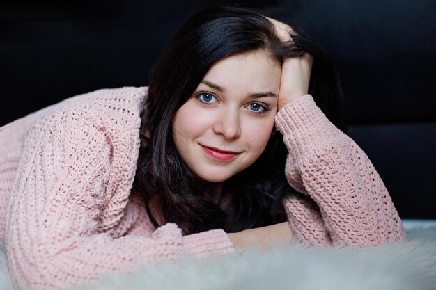 Mooie brunette in roze kleding op een donkere achtergrond kijkt naar de camera