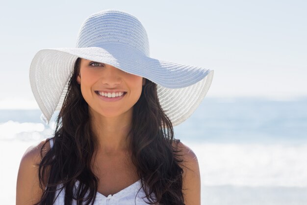 Mooie brunette in witte sunhat die bij camera glimlacht