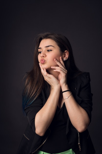 Mooie brunette jonge vrouw in zwarte jas en groene broek