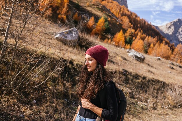Mooie brunette Kaukasisch meisje met lang krullend haar wandelingen in de bergen met een rode wollen muts