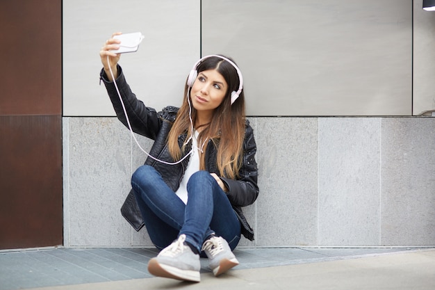 Mooie brunette luisteren muziek en praten met mobiel