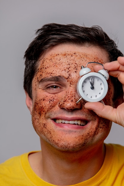 Mooie brunette man met koffiebonen masker en wekker