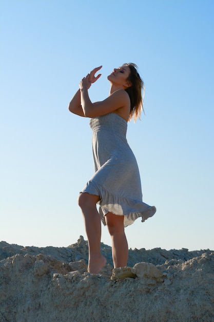 Mooie brunette meisje dansen en kijken naar de sun.girl in een witte jurk in de woestijn tegen de blauwe hemel.