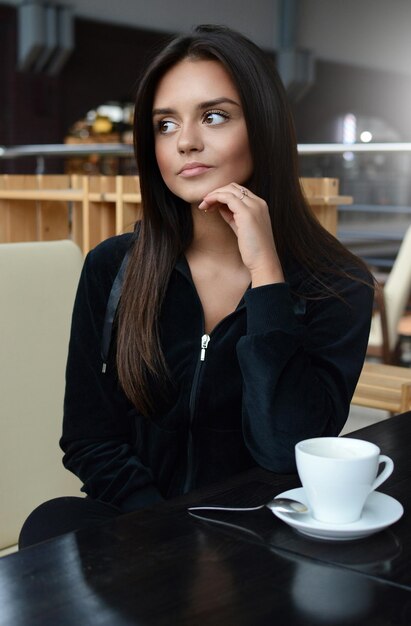 Mooie brunette meisje drinkt thee of koffie in een café