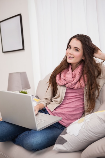 Mooie brunette met behulp van laptop op de bank