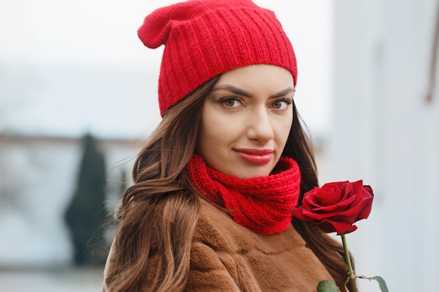 Mooie brunette met rode roos in haar handen