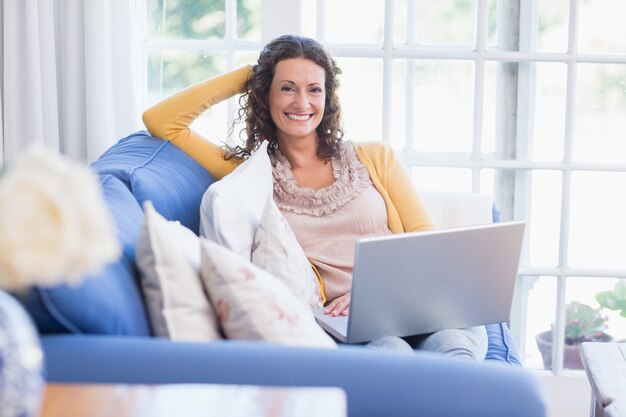 Mooie brunette ontspannen op de bank met laptop