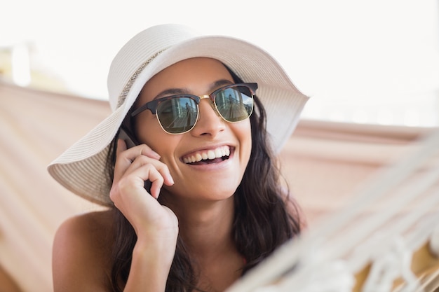 Mooie brunette ontspannen op een hangmat en bellen met haar mobiele telefoon