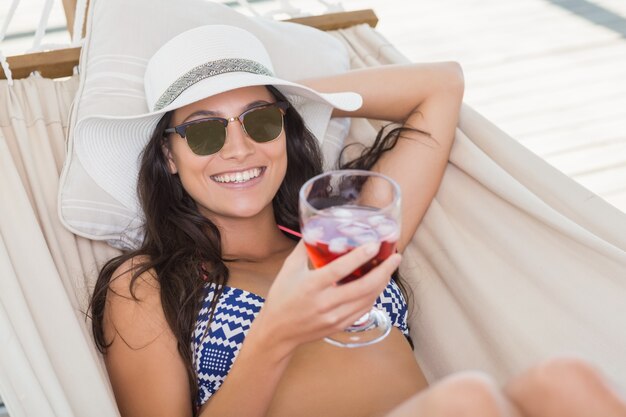 Mooie brunette ontspannen op een hangmat en cocktail drinken