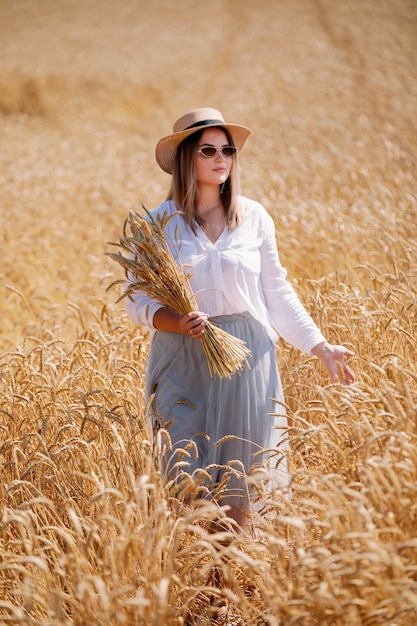 Mooie brunette plus size dame in tarweveld bij zonsondergang.