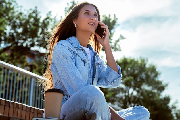 Mooie brunette vrouw communiceert met vrienden met behulp van mobiele telefoon.