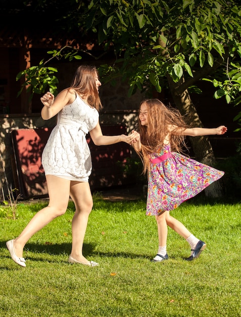 Mooie brunette vrouw een jong meisje die ands vasthoudt en danst op de werf