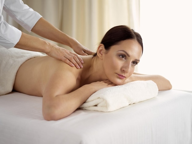 Mooie brunette vrouw genieten van procedure van rugmassage in spa salon. Schoonheidsconcept.