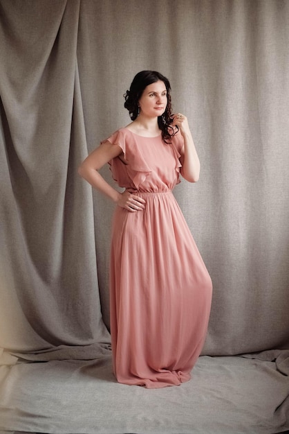 Mooie brunette vrouw in een roze jurk op een achtergrond van linnen stof