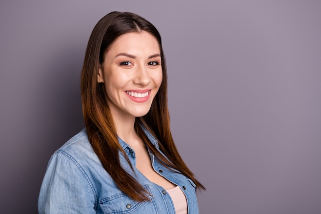 mooie brunette vrouw in spijkerbroek shirt poseren tegen de paarse muur