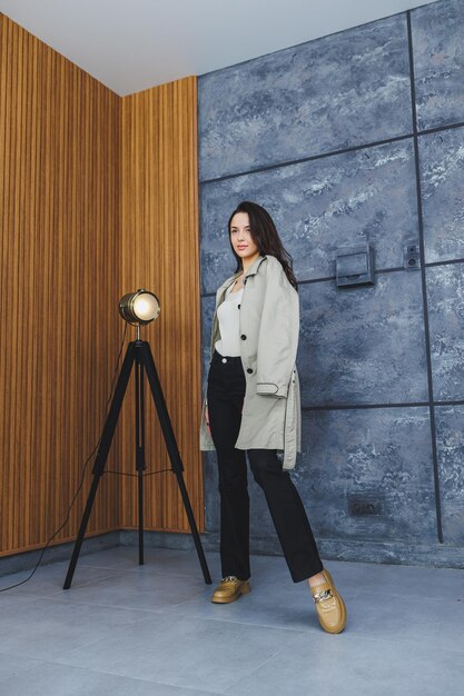 Mooie brunette vrouw in zwarte broek en bruine loafers poseren in studio