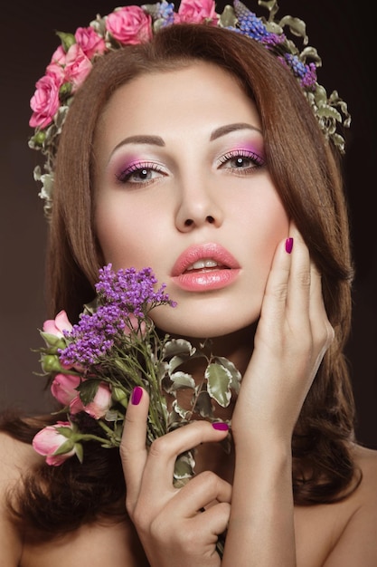 Mooie brunette vrouw met een zachte romantische make-up roze lippen met bloemen De schoonheid van het gezicht