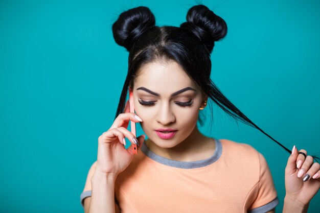 Mooie brunette vrouw met haarmuis glimlachend en pratend aan de telefoon op de blue