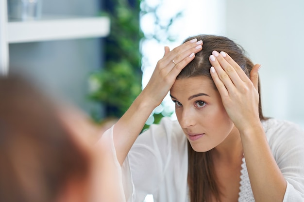 Mooie brunette vrouw met huidproblemen in de badkamer