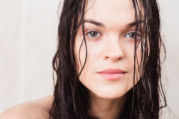 Mooie brunette vrouw met lang nat haar poseren in de douche