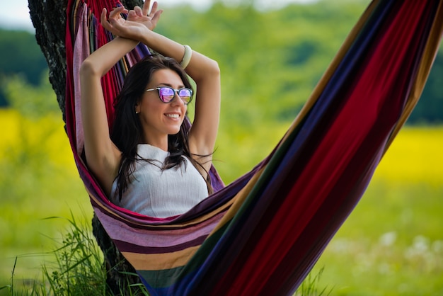 Mooie brunette vrouw met zonnebril ligt in een hangmat