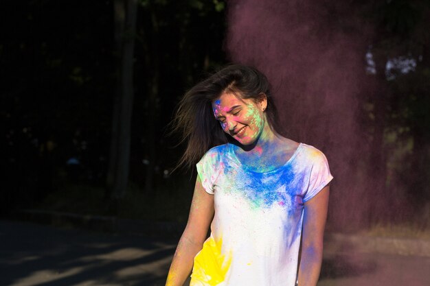 Mooie brunette vrouw poseren met exploderende Holi-poeder in het park