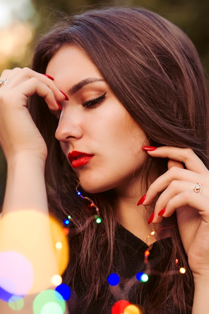 Mooie brunette vrouw poseren met slingers op de stad straat. Close-up portret