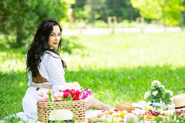 mooie brunette vrouw rusten in park zittend op een picknickdeken Ontspannen in de natuur