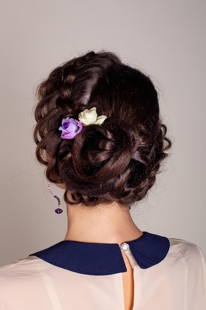 Mooie brunette vrouw terug met elegante bruiloft kapsel en bloemen