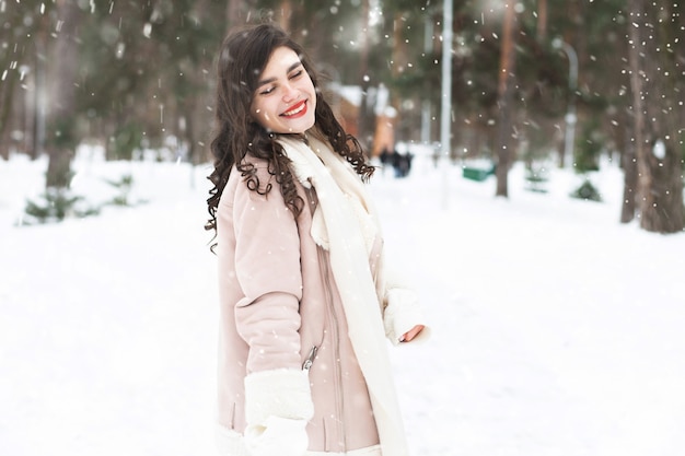 Mooie brunette vrouw wandelen in het bos tijdens sneeuwval. Ruimte voor tekst