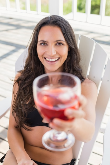 Mooie brunette zittend op een stoel en cocktail drinken