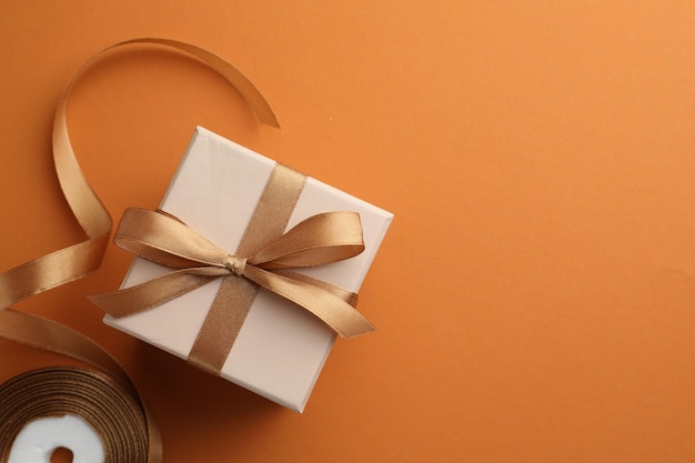 Mooie cadeau doos met gouden strik en lint op oranje achtergrond bovenkant Ruimte voor tekst