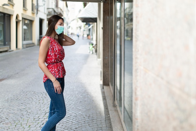 Mooie charmante jongedame die wakker wordt in een stadsstraat en naar een winkelraam kijkt