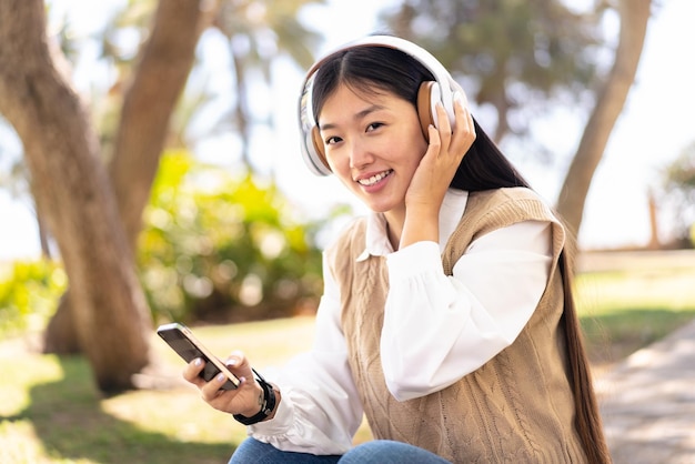 Mooie Chinese vrouw buitenshuis met behulp van mobiele telefoon